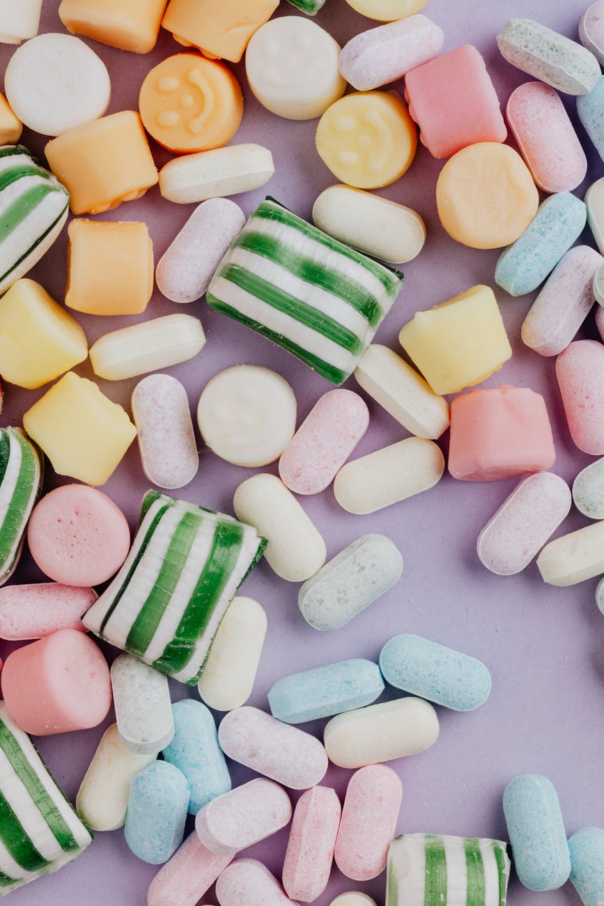 top view of various chewy candies on light purple background